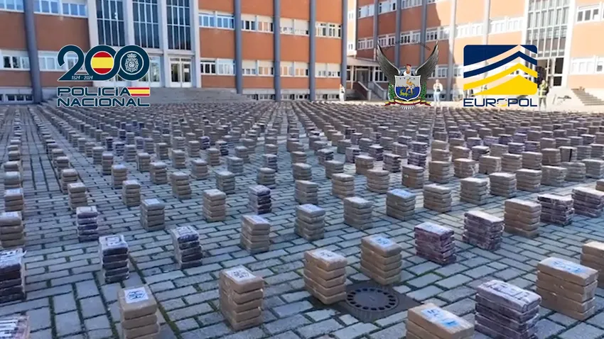 Centenares de paquetes rectangulares alineados sobre un pavimento ante un edificio, con emblemas policiales.